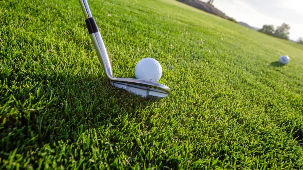 golfboll och en golfklubba på en golfbana